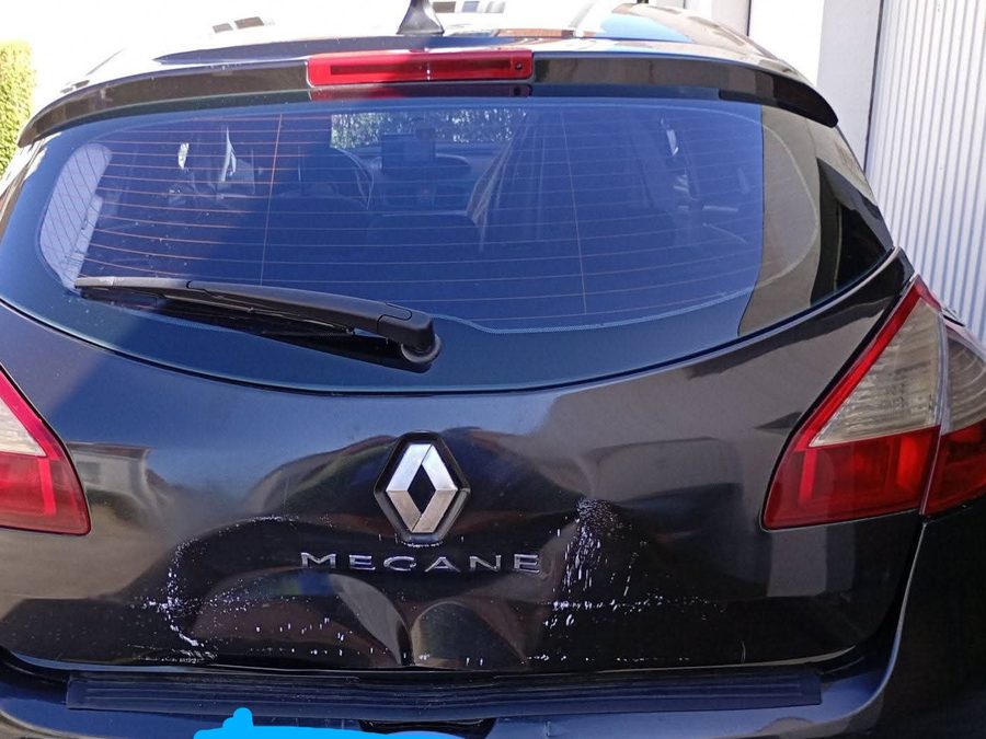 Hayon de Renault Mégane endommagé, traces blanches laissées par la porte du garage